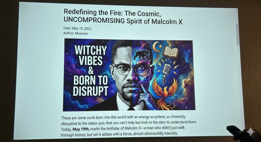 A photo of a projector screen displaying a web article titled "Redefining the Fire: The Cosmic, UNCOMPROMISING Spirit of Malcolm X" dated May 19, 2022. The article features a digital illustration of Malcolm X split down the middle: one side is a classic black-and-white portrait, and the other side features a vibrant cosmic galaxy background with text that reads "Witchy Vibes & Born to Disrupt." The graphic includes symbolic elements like a black panther, a crescent moon and star, an open book, a retro microphone, and a rising phoenix.
